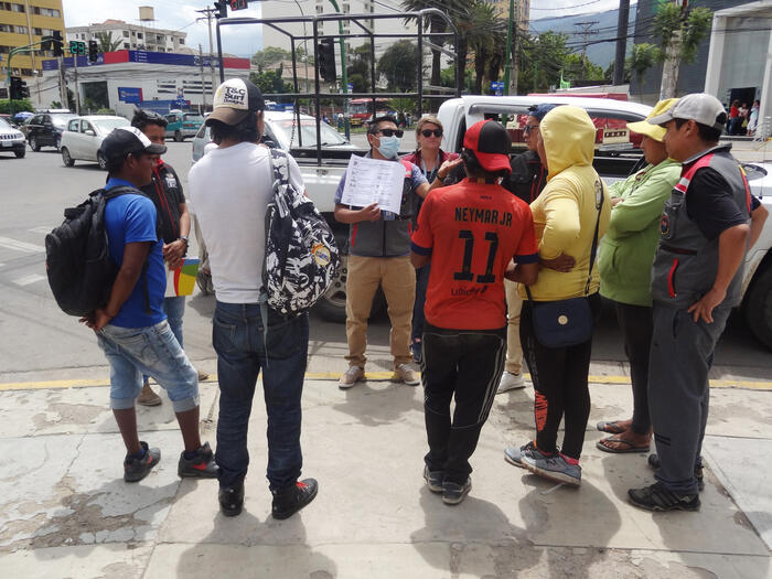 Bolivien, Cochabamba: Comundo-Fachperson Lisa Macconi und ein Mitarbeiter der „Fundación Estrellas en la calle“ informieren eine Gruppe von Obdachlosen über den Corona-Virus. 
