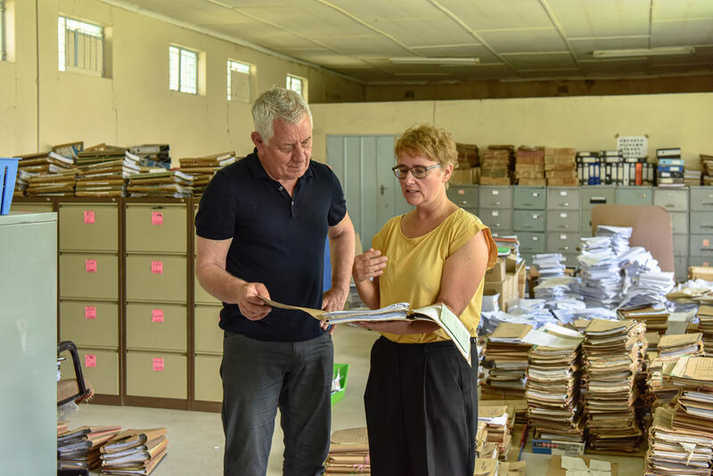 Comundo-Botschafter Röbi Koller ist zu Besuch in meinem Projekt: Ich erkläre ihm, wie man in den Bergen von Papier die gesuchte Akte findet.