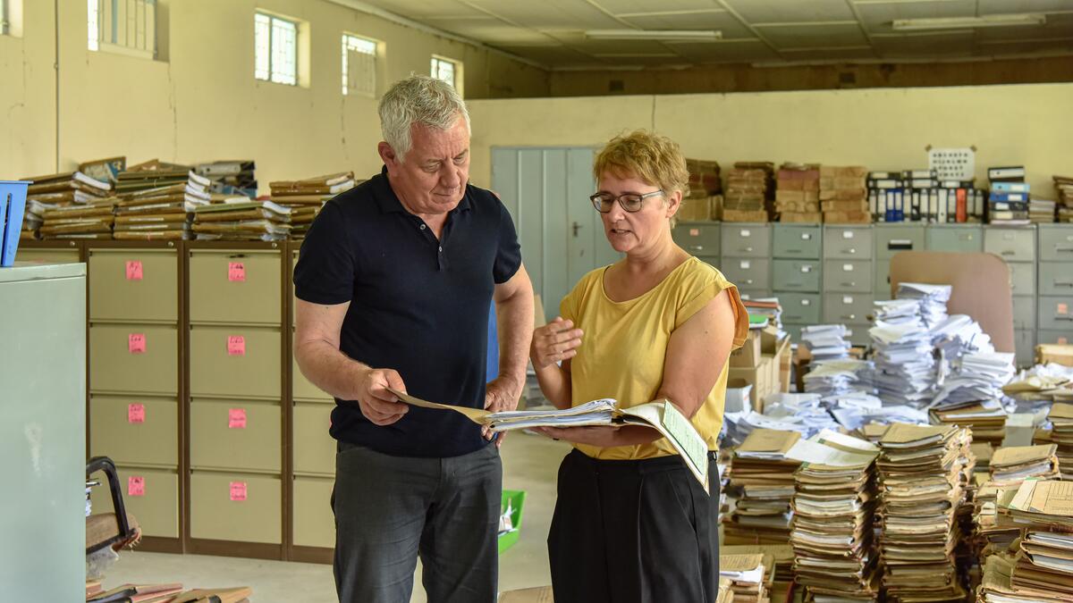 Comundo-Botschafter Röbi Koller ist zu Besuch in meinem Projekt: Ich erkläre ihm, wie man in den Bergen von Papier die gesuchte Akte findet.